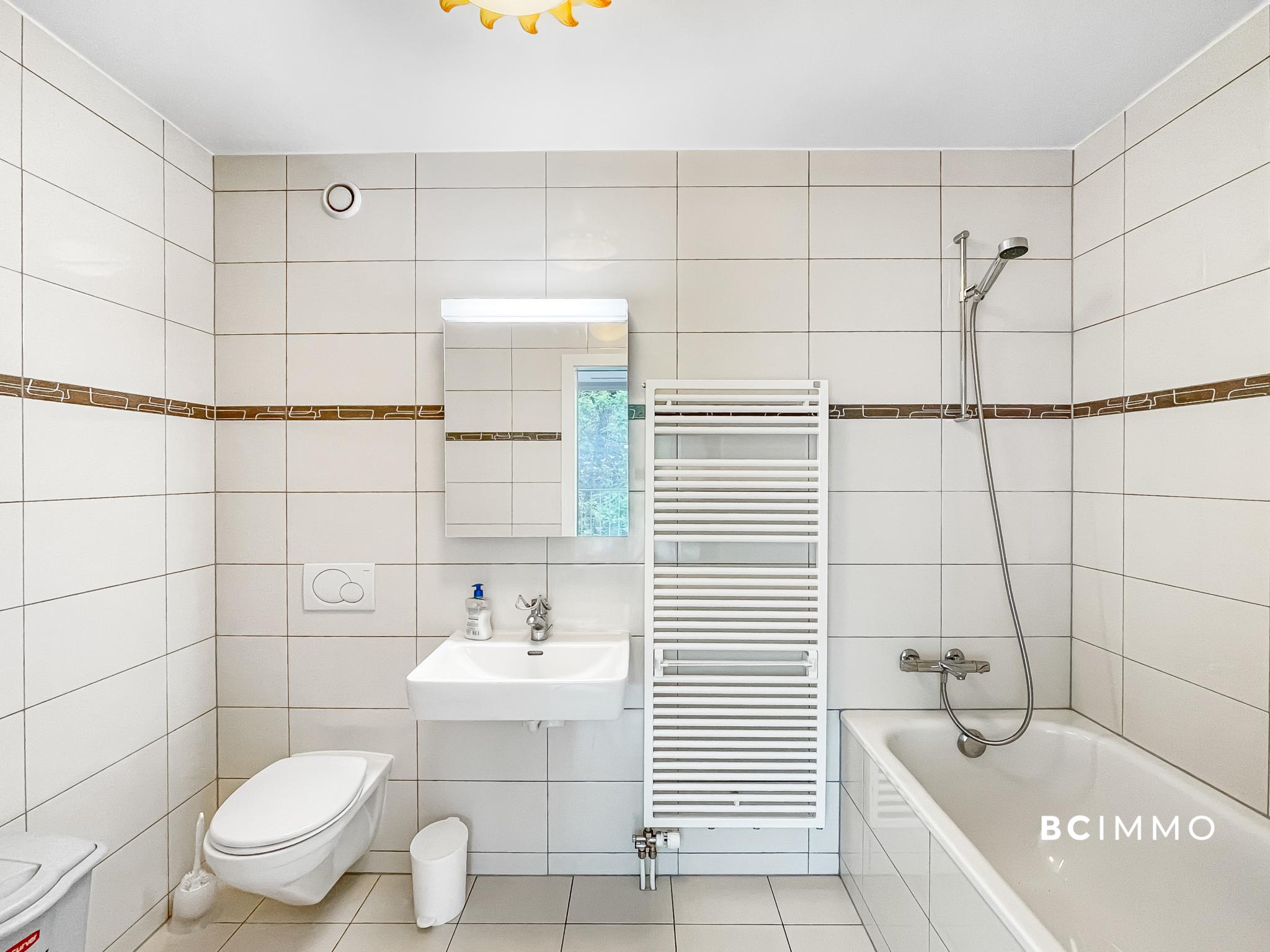 Helles Badezimmer mit Wanne, WC und Wandheizkörper
